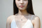 Necklace with a cross pendant on a mannequin wearing a white top.